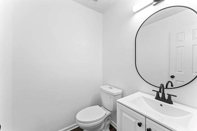 bathroom with vanity, toilet, and baseboards