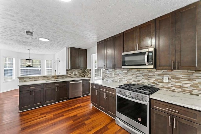 kitchen with visible vents, dark wood-type flooring, a sink, tasteful backsplash, and appliances with stainless steel finishes