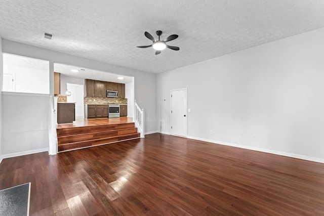 unfurnished living room featuring visible vents, a ceiling fan, a textured ceiling, baseboards, and dark wood-style flooring