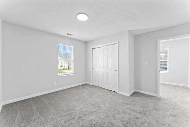 unfurnished bedroom with a closet, baseboards, carpet, and visible vents