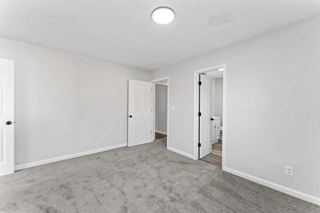 unfurnished bedroom with connected bathroom, baseboards, carpet floors, and a textured ceiling