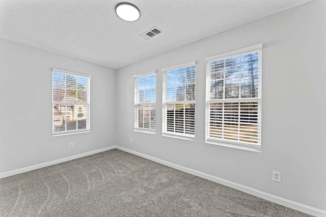 carpeted spare room with visible vents, baseboards, and a textured ceiling