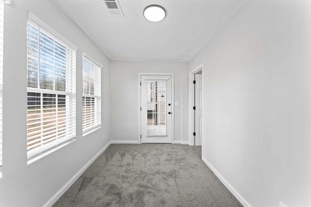 hall with baseboards, visible vents, and carpet floors