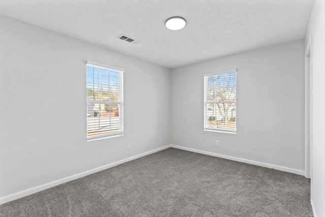 empty room featuring visible vents, baseboards, a healthy amount of sunlight, and carpet flooring