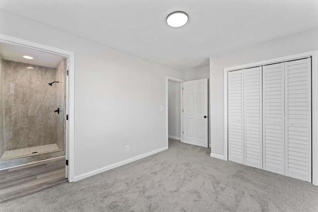 unfurnished bedroom with a closet, baseboards, ensuite bath, and carpet flooring