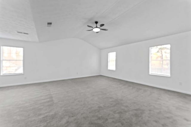 empty room featuring ceiling fan, baseboards, carpet, and vaulted ceiling