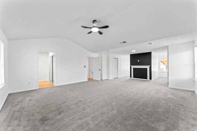 unfurnished living room featuring visible vents, lofted ceiling, carpet flooring, and a ceiling fan