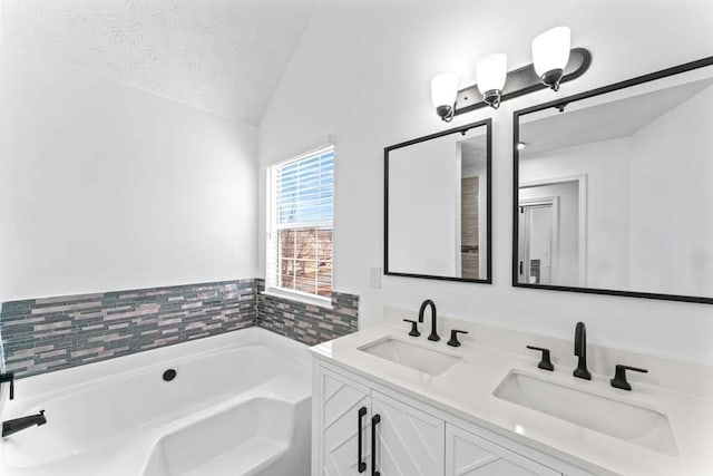 bathroom with a sink, a textured ceiling, a bath, and vaulted ceiling