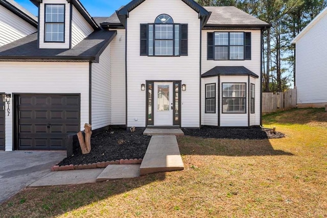 view of front of house with a front yard, fence, driveway, and a shingled roof