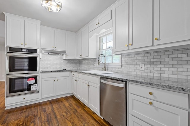 256 Teresa Ln, Loganville, GA 30052 - kitchen featuring stainless steel appliances, a sink, white cabinets, dark wood finished floors, and decorative backsplash
