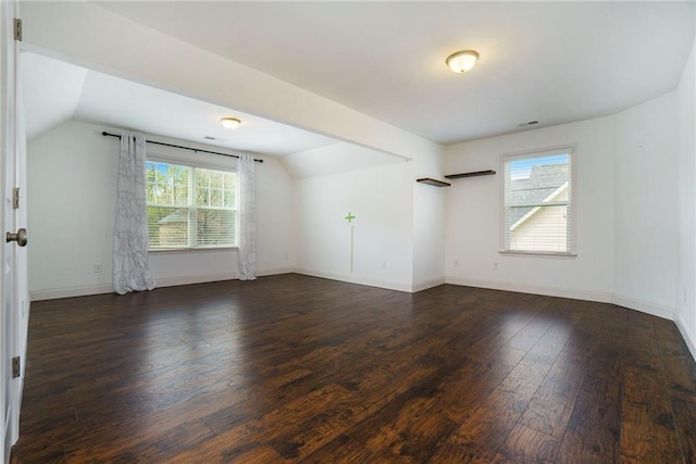 spare room with lofted ceiling, plenty of natural light, and dark hardwood / wood-style floors