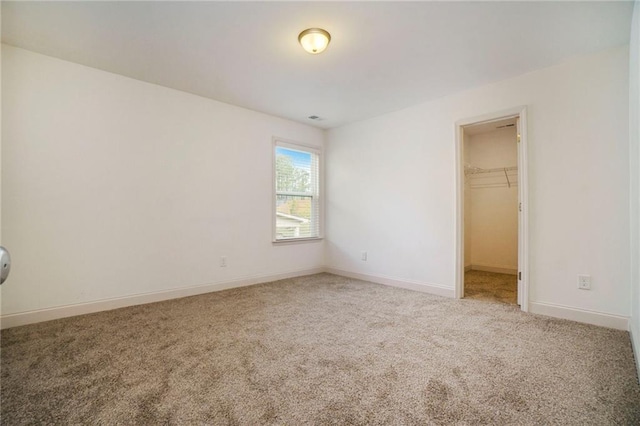 unfurnished bedroom featuring a walk in closet, a closet, and carpet