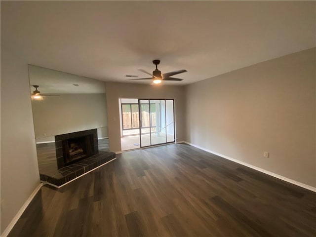 unfurnished living room with dark wood-style floors, baseboards, a tile fireplace, a ceiling fan, and visible vents