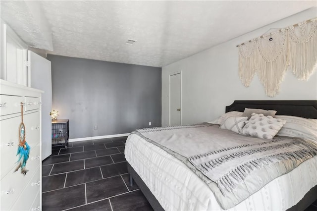 bedroom featuring dark tile patterned flooring and a textured ceiling