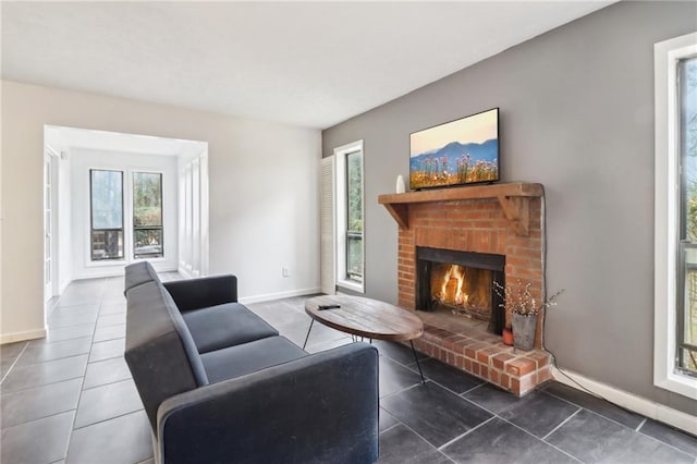 living room featuring a brick fireplace and dark tile patterned floors