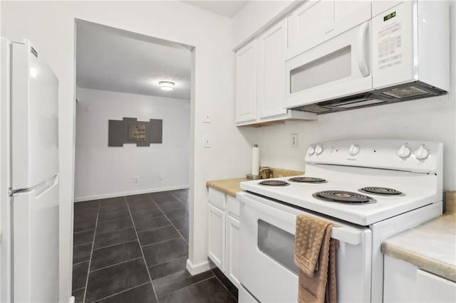 kitchen with white cabinetry, dark tile patterned flooring, and white appliances