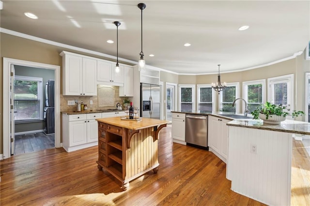 kitchen with crown molding, appliances with stainless steel finishes, a spacious island, and a healthy amount of sunlight