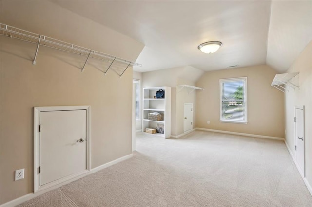 interior space featuring baseboards, light carpet, and lofted ceiling