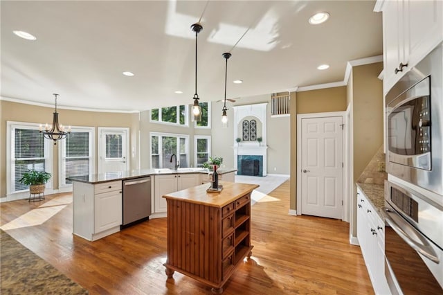 kitchen with ornamental molding, a kitchen island with sink, wooden counters, appliances with stainless steel finishes, and a premium fireplace