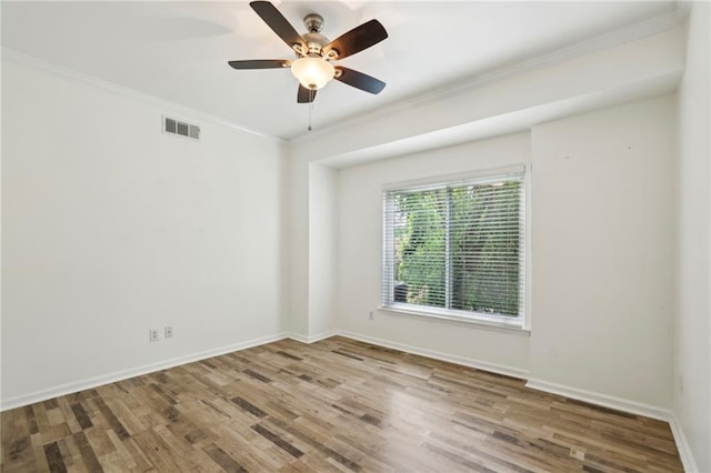 empty room featuring crown molding, visible vents, and wood finished floors