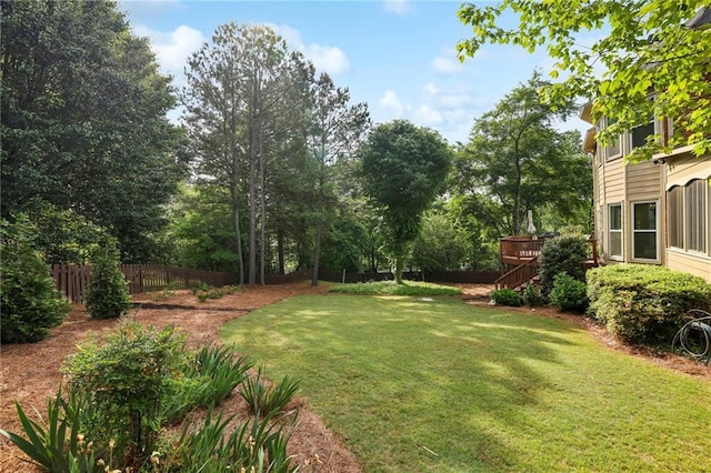 view of yard featuring a deck, fence, and stairs
