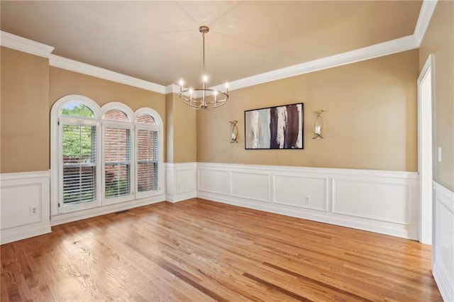 spare room featuring crown molding, an inviting chandelier, and light wood finished floors