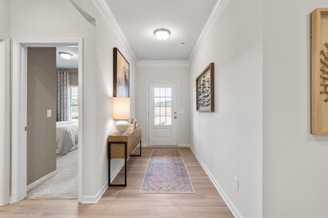 doorway to outside featuring ornamental molding, visible vents, light wood-style floors, and baseboards