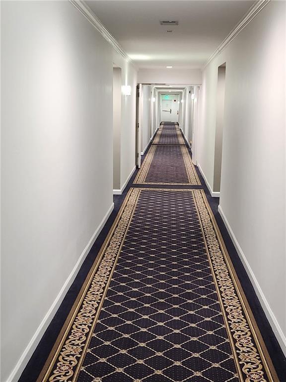 hall featuring ornamental molding, visible vents, and baseboards