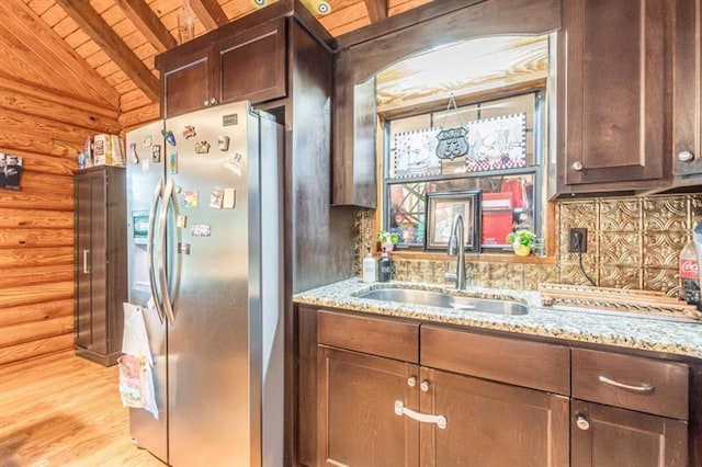 kitchen with rustic walls, sink, lofted ceiling with beams, wooden ceiling, and stainless steel fridge with ice dispenser