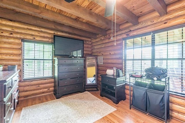 bedroom featuring beam ceiling, rustic walls, and light hardwood / wood-style floors