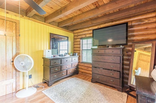 bedroom with beamed ceiling, light wood-type flooring, rustic walls, and wooden ceiling