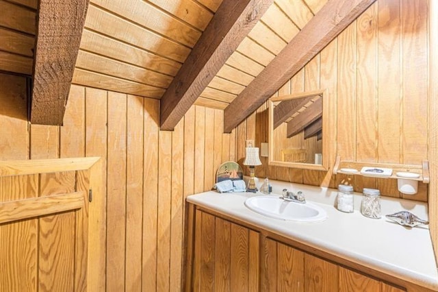 bathroom with beamed ceiling, vanity, wood walls, and wooden ceiling