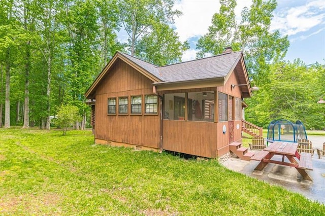 rear view of property with a patio area, a sunroom, a yard, and a trampoline