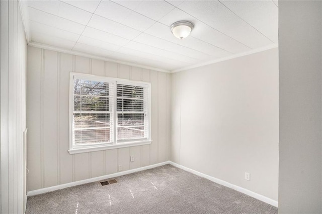 empty room with baseboards, carpet flooring, visible vents, and crown molding