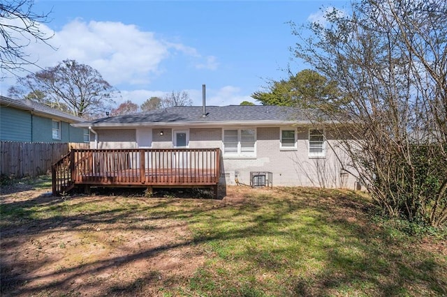 back of property featuring a yard, brick siding, fence, and a wooden deck