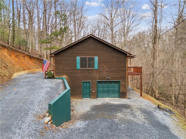 view of home's exterior featuring a garage, gravel driveway, and a view of trees