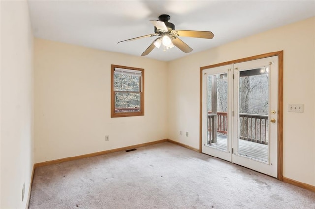 carpeted empty room with ceiling fan, plenty of natural light, visible vents, and baseboards