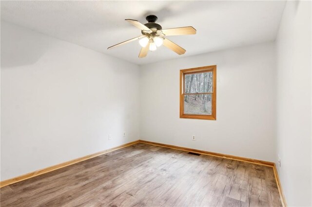 spare room featuring visible vents, baseboards, ceiling fan, and wood finished floors