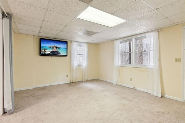 carpeted spare room featuring a drop ceiling