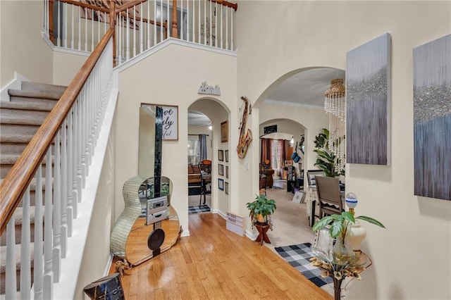 entryway with crown molding, a towering ceiling, and wood-type flooring