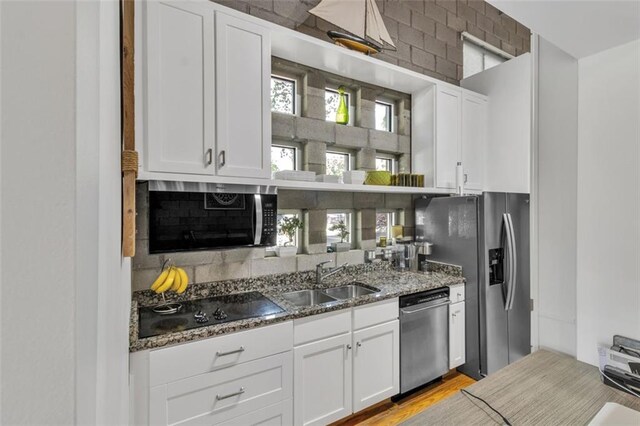 kitchen featuring appliances with stainless steel finishes, a sink, stone countertops, tasteful backsplash, and white cabinets