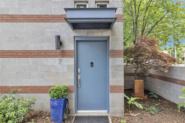 view of exterior entry featuring brick siding and fence