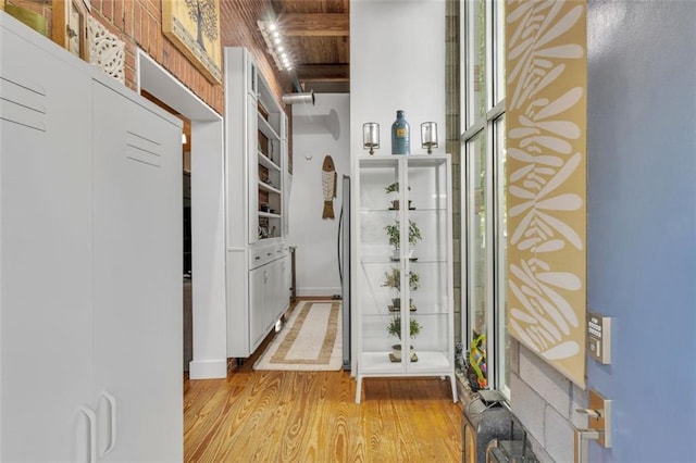 doorway to outside featuring light wood-style flooring and wooden ceiling