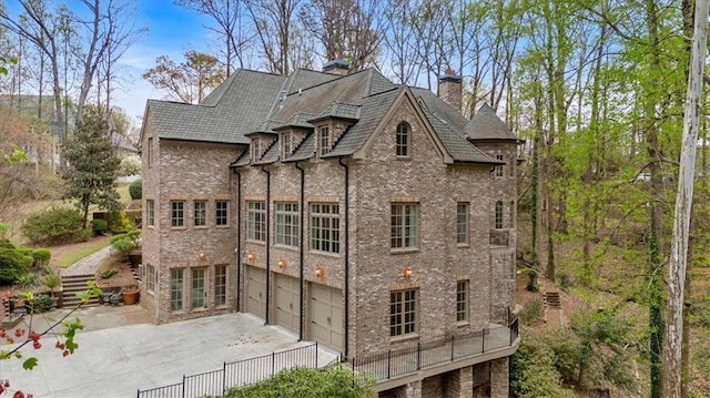 view of property exterior featuring driveway, an attached garage, and a chimney