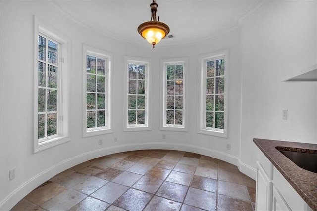 unfurnished dining area with baseboards, ornamental molding, visible vents, and stone tile floors