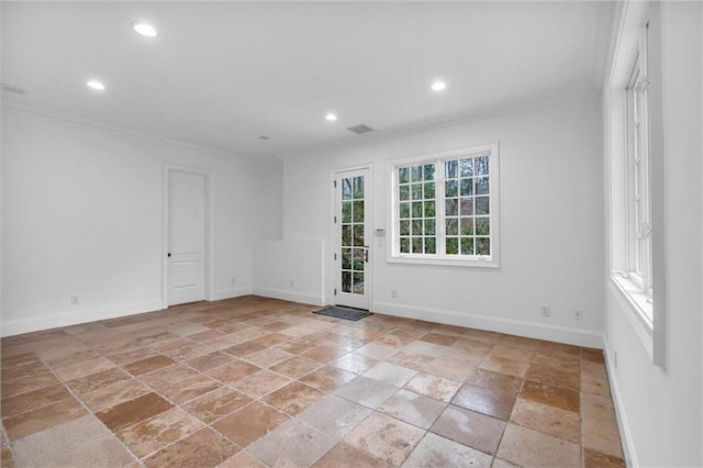 empty room with baseboards, crown molding, and stone tile floors