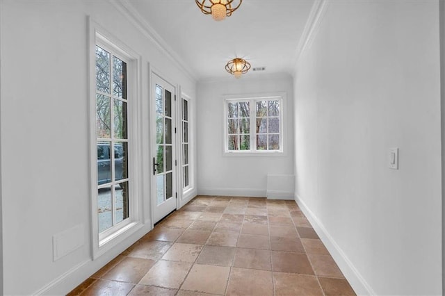 doorway with baseboards, visible vents, crown molding, and stone tile flooring