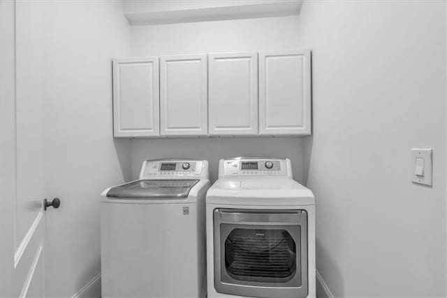 washroom featuring baseboards, washer and dryer, and cabinet space