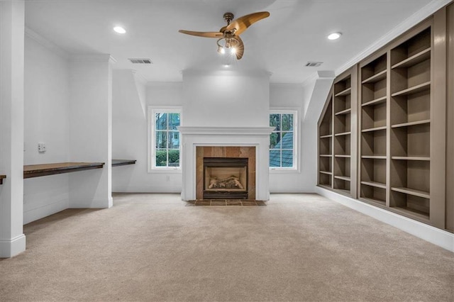 unfurnished living room featuring crown molding, carpet flooring, ceiling fan, visible vents, and a tile fireplace