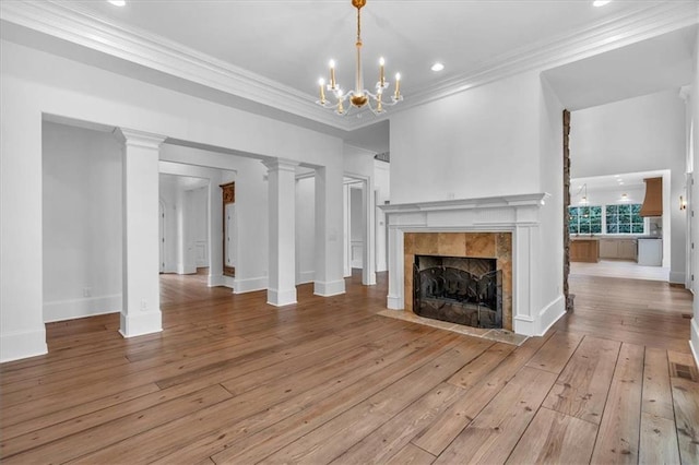 unfurnished living room featuring an inviting chandelier, ornamental molding, baseboards, hardwood / wood-style flooring, and a tiled fireplace